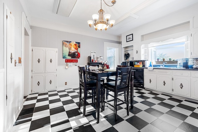 dining room featuring tile patterned floors, a decorative wall, an inviting chandelier, and crown molding