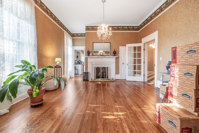 living room with a fireplace, french doors, ornamental molding, hardwood / wood-style floors, and a notable chandelier