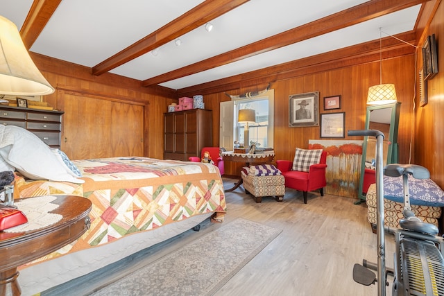 bedroom featuring light hardwood / wood-style floors, wooden walls, and beam ceiling