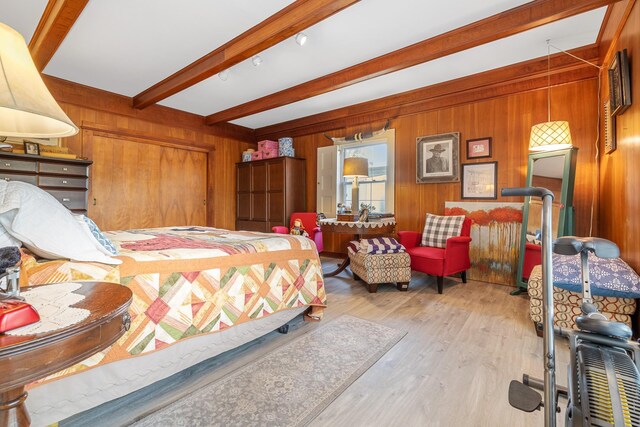 bedroom with wood finished floors, wood walls, and beam ceiling