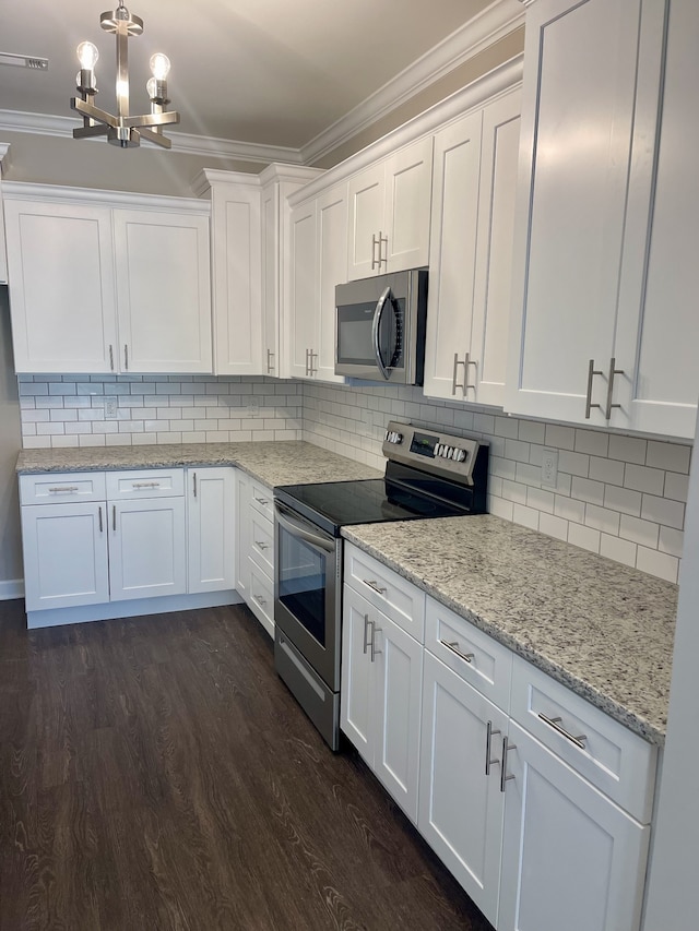 kitchen with dark hardwood / wood-style floors, white cabinetry, an inviting chandelier, stainless steel appliances, and ornamental molding