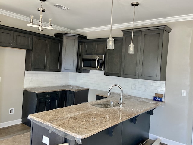 kitchen with a breakfast bar area, crown molding, decorative light fixtures, and sink