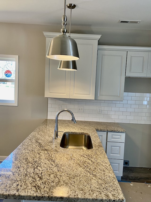 kitchen with tasteful backsplash, sink, and white cabinets