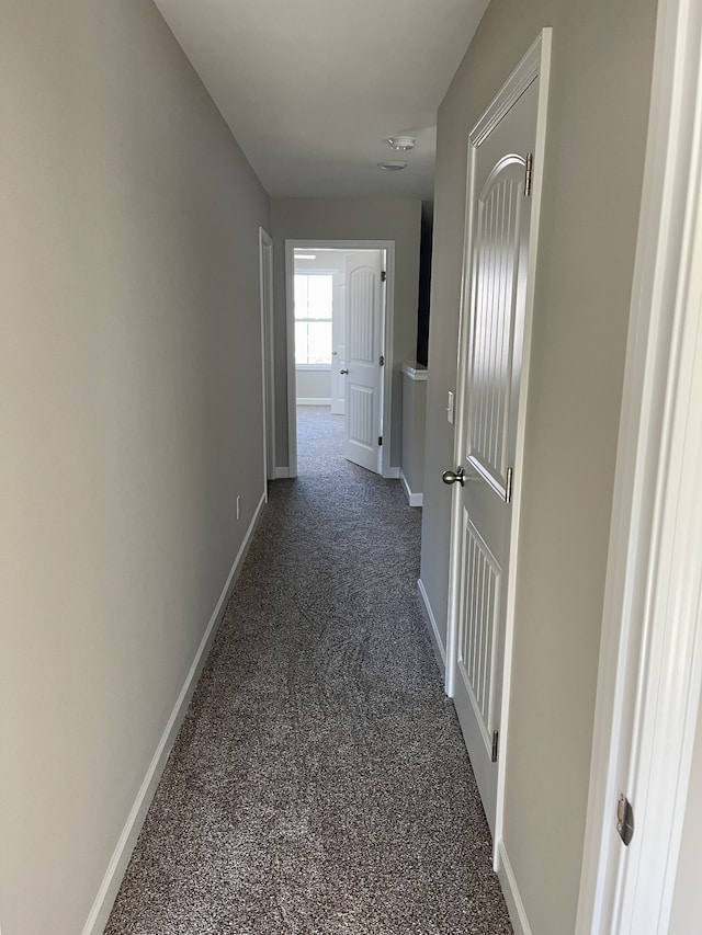 hallway featuring dark colored carpet