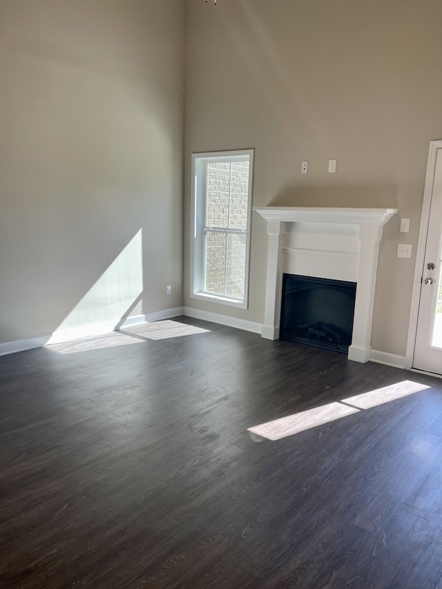 unfurnished living room featuring dark wood-type flooring and plenty of natural light