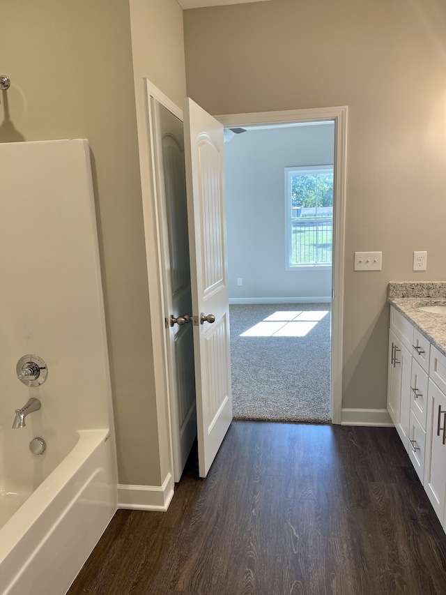 bathroom with vanity, hardwood / wood-style floors, and washtub / shower combination