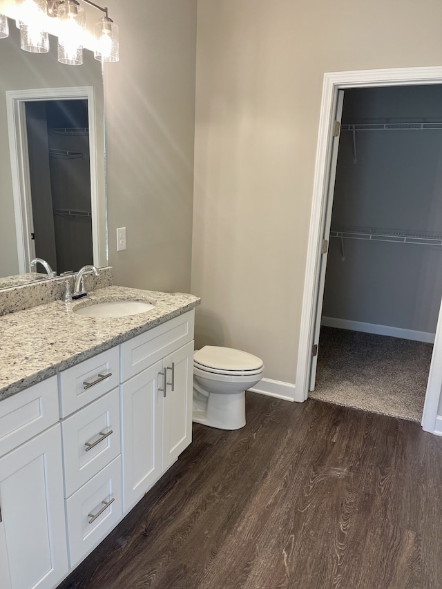 bathroom with hardwood / wood-style floors, vanity, and toilet