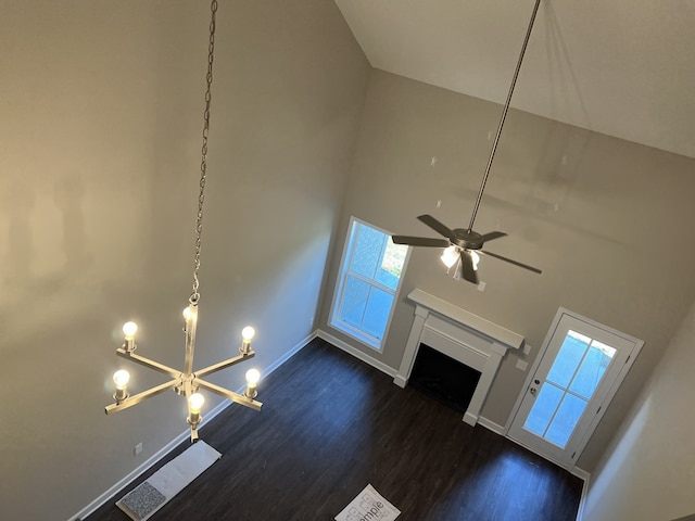 unfurnished living room with ceiling fan with notable chandelier, dark hardwood / wood-style flooring, and high vaulted ceiling