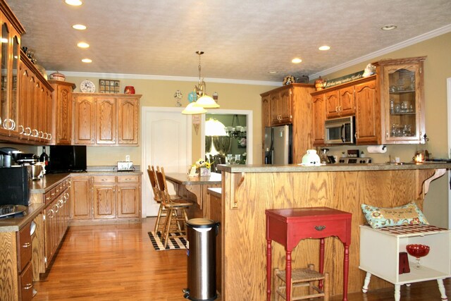 kitchen featuring crown molding, a breakfast bar area, light hardwood / wood-style flooring, and stainless steel appliances