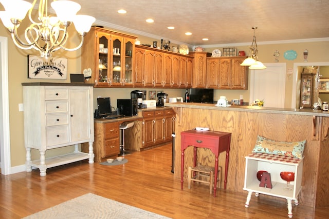 kitchen with ornamental molding, a chandelier, light hardwood / wood-style floors, and a breakfast bar area