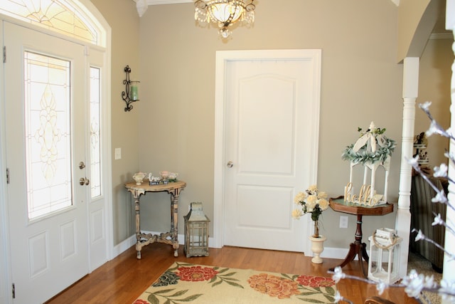 foyer featuring ornamental molding, hardwood / wood-style flooring, a chandelier, and a healthy amount of sunlight