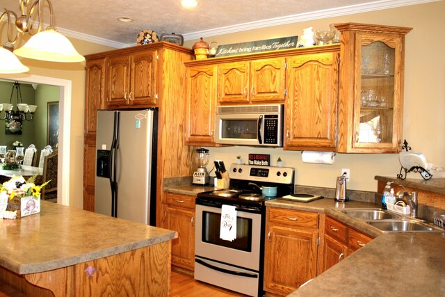 kitchen with stainless steel appliances, a textured ceiling, ornamental molding, sink, and a notable chandelier