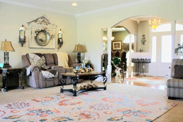 carpeted living room with a notable chandelier and ornamental molding