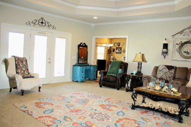 living room with ornamental molding, french doors, a tray ceiling, carpet floors, and a notable chandelier