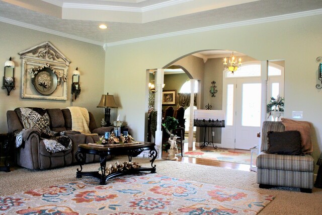 carpeted living room featuring ornamental molding and a notable chandelier