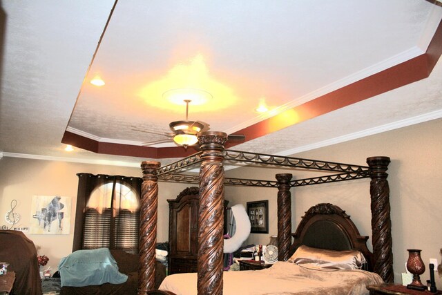 bedroom with ornamental molding, a tray ceiling, and ceiling fan