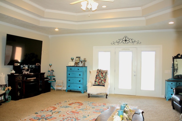 carpeted living room featuring ceiling fan, a raised ceiling, and crown molding