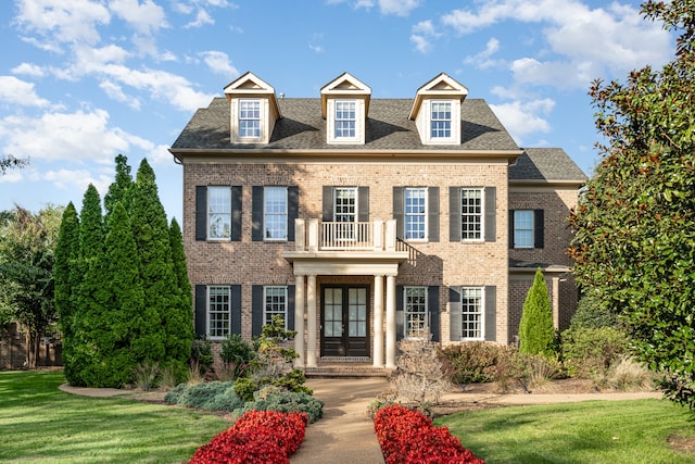 colonial inspired home with a front yard, french doors, and a balcony