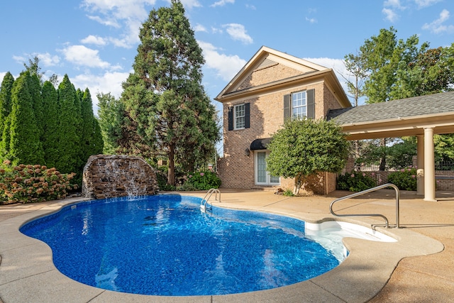 view of swimming pool with pool water feature and a patio