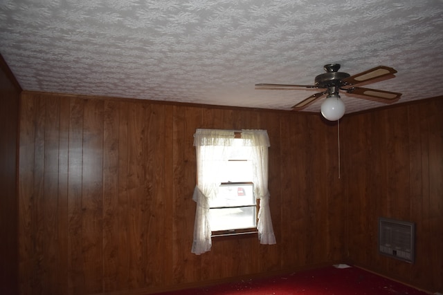 empty room featuring wood walls, ceiling fan, and plenty of natural light