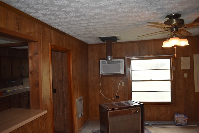 kitchen featuring a textured ceiling, wooden walls, ceiling fan, and a wall mounted air conditioner