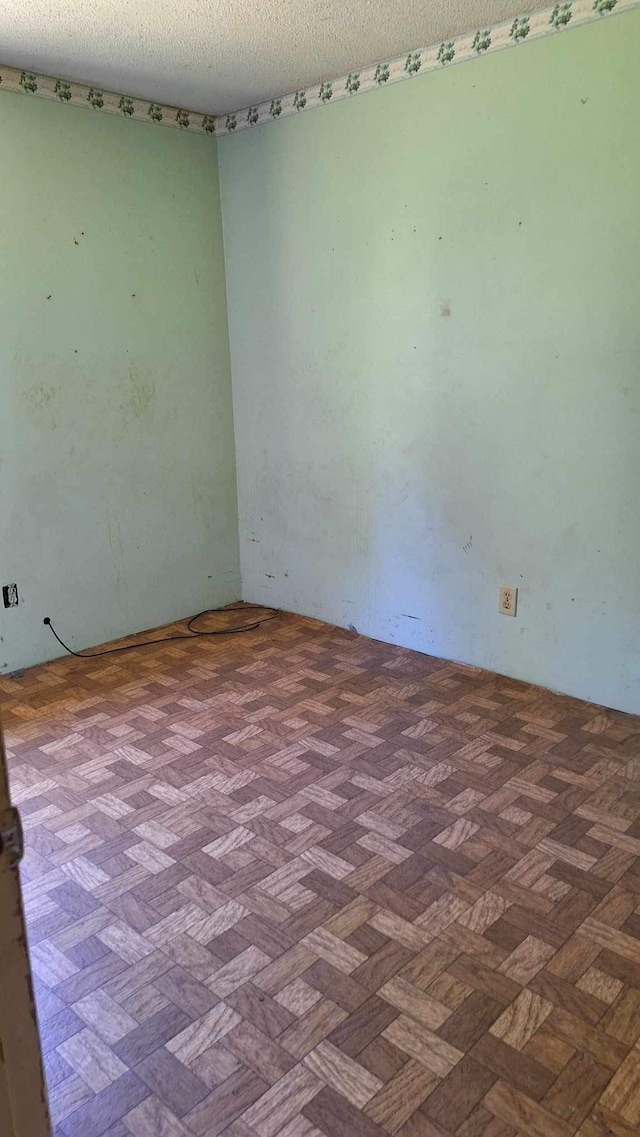 spare room featuring a textured ceiling and parquet flooring