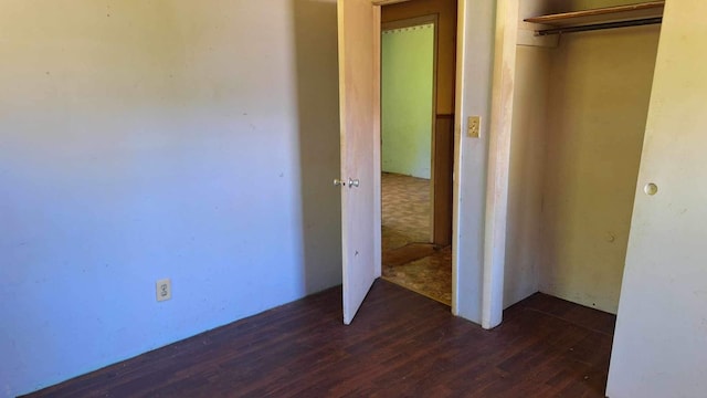 unfurnished bedroom with dark wood-type flooring and a closet