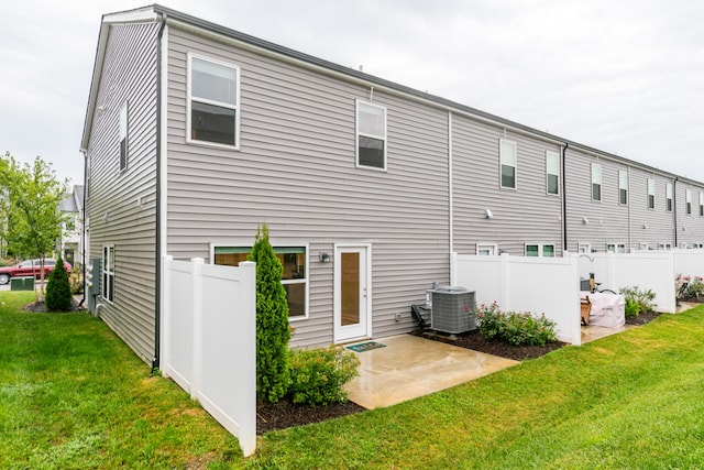 rear view of house featuring a lawn, central AC, and a patio area