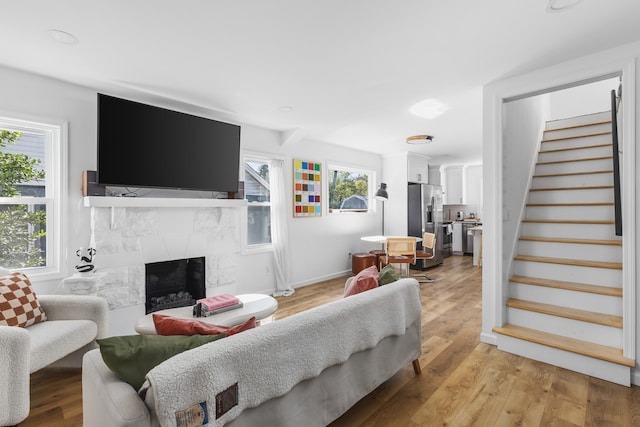 living room featuring a healthy amount of sunlight, a high end fireplace, and light hardwood / wood-style flooring