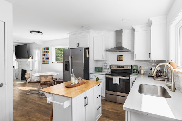 kitchen with white cabinets, sink, a kitchen island, wall chimney range hood, and stainless steel appliances