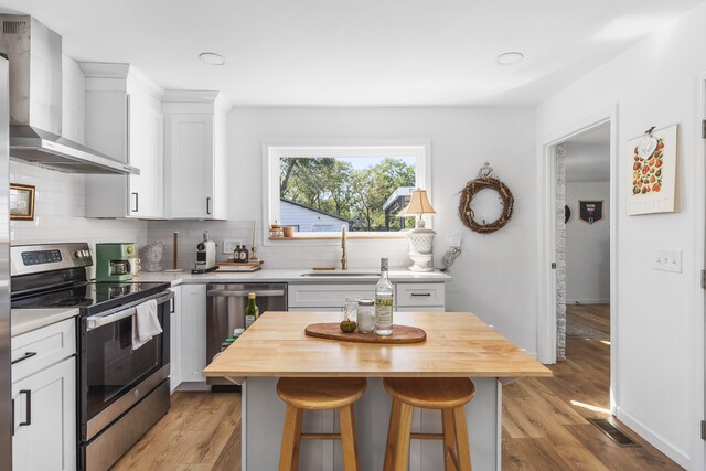 kitchen featuring appliances with stainless steel finishes, a center island, butcher block counters, and a breakfast bar