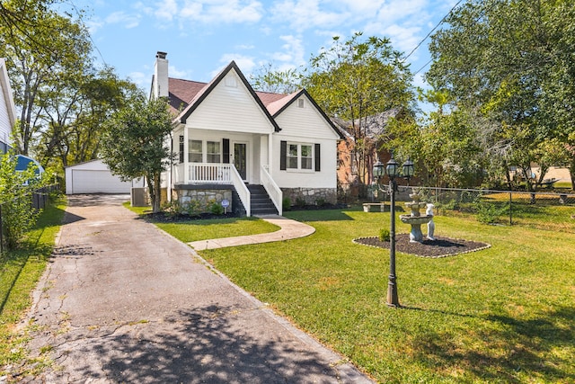 view of front of home featuring covered porch, cooling unit, an outdoor structure, a garage, and a front yard