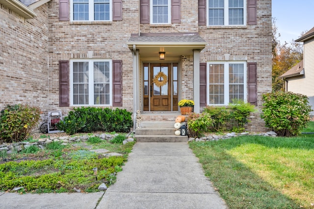 view of exterior entry featuring a lawn