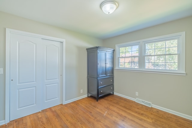 unfurnished bedroom with light wood-type flooring and a closet