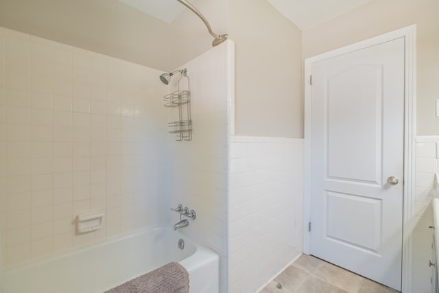 bathroom with tile walls, tile patterned floors, and tiled shower / bath