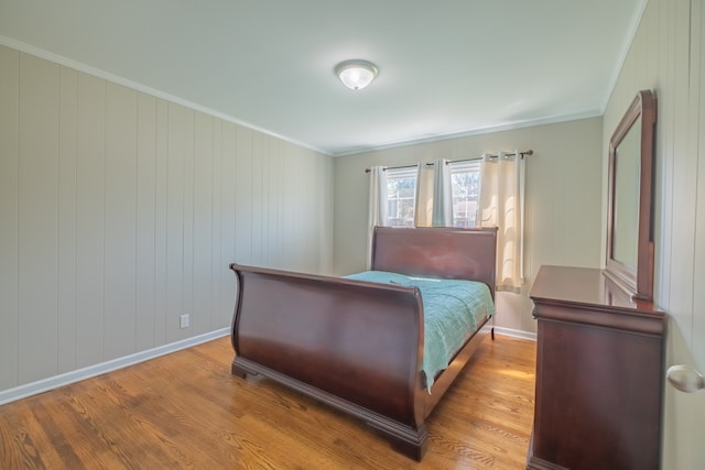 bedroom with wooden walls, light hardwood / wood-style flooring, and ornamental molding