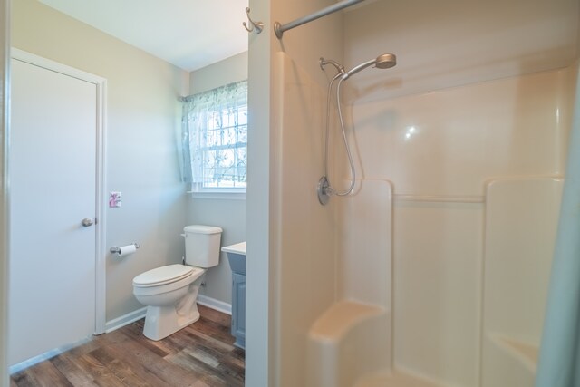 bathroom featuring walk in shower, hardwood / wood-style flooring, vanity, and toilet