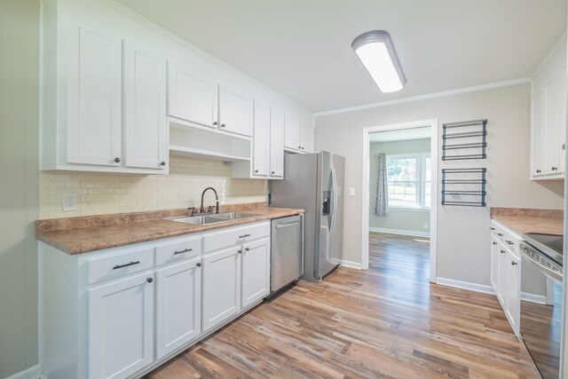 kitchen with stainless steel appliances, white cabinets, crown molding, and sink