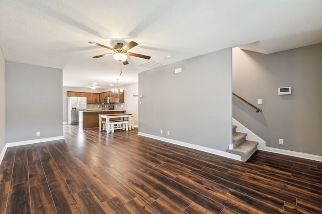 unfurnished living room with dark wood-type flooring, a textured ceiling, and ceiling fan