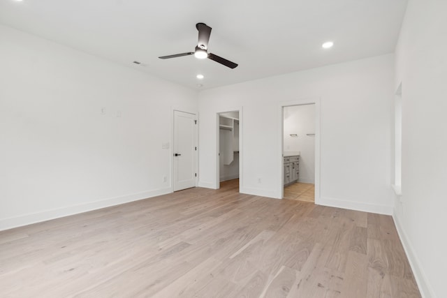 unfurnished bedroom with a walk in closet, ceiling fan, light hardwood / wood-style flooring, connected bathroom, and a closet