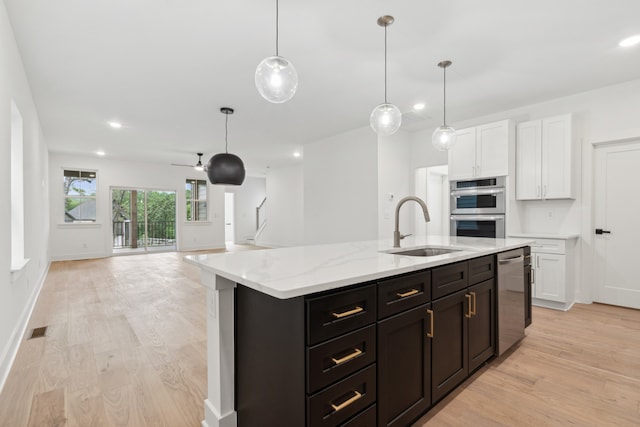 kitchen featuring appliances with stainless steel finishes, light wood-type flooring, hanging light fixtures, and sink