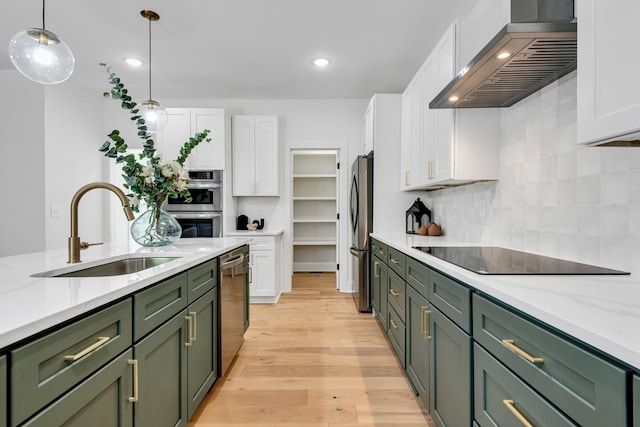 kitchen with appliances with stainless steel finishes, sink, wall chimney range hood, white cabinets, and green cabinets