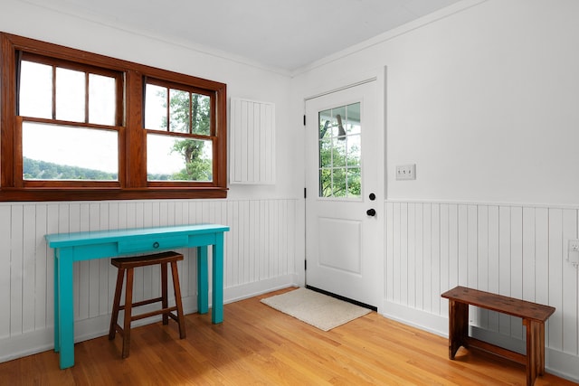 doorway to outside with ornamental molding and light hardwood / wood-style floors