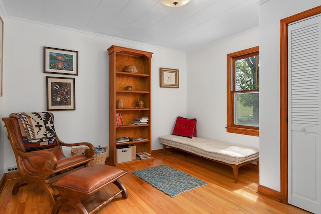 sitting room featuring ornamental molding and light wood-type flooring