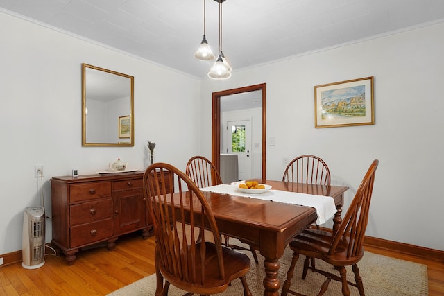 dining room with crown molding and light hardwood / wood-style flooring