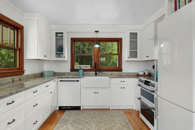 kitchen with sink, white cabinetry, light stone counters, light wood-type flooring, and white appliances