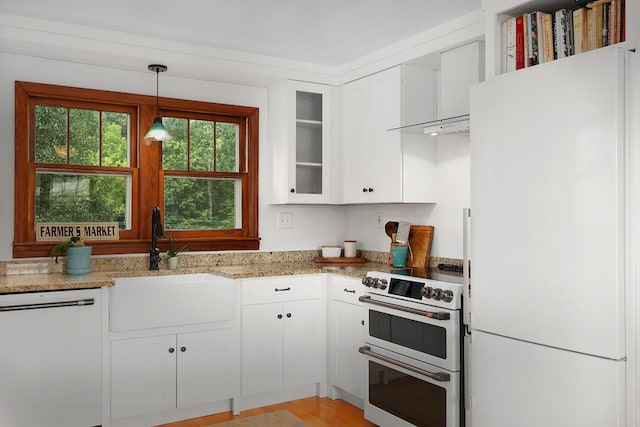 kitchen with sink, light stone counters, hanging light fixtures, white appliances, and white cabinets