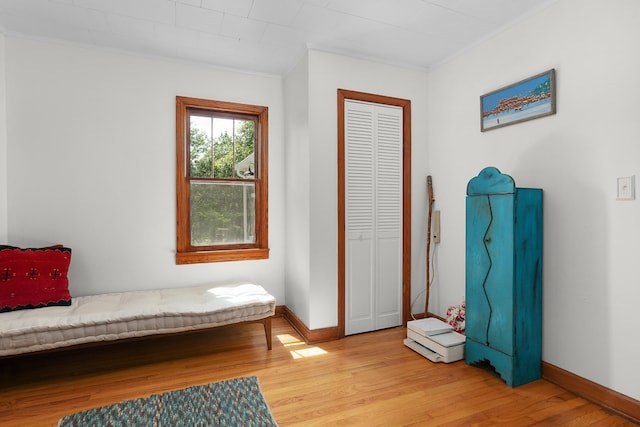 bedroom with ornamental molding, light hardwood / wood-style floors, and a closet