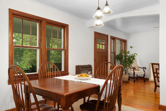 dining space with hardwood / wood-style flooring, ornamental molding, and heating unit