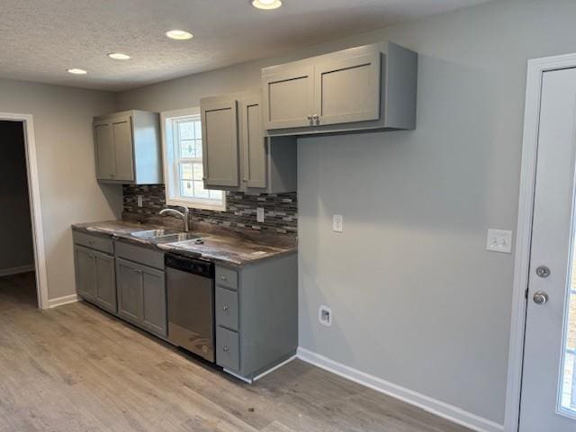 kitchen featuring gray cabinetry, sink, tasteful backsplash, light hardwood / wood-style flooring, and stainless steel dishwasher